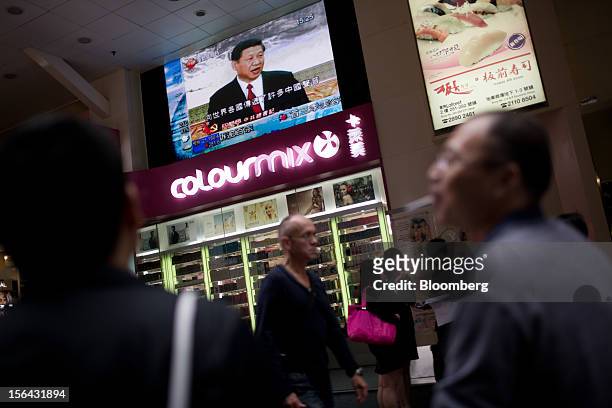 Pedestrians pass by a monitor showing a news broadcast of Xi Jinping, general secretary of the Communist Party of China, during a news conference...