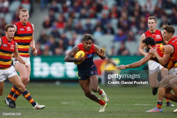 Kysaiah Pickett of the Demons runs with the ball under pressure during the round 19 AFL match between Melbourne Demons and Adelaide Crows at...