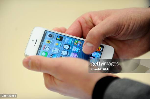 Person looks at an iPhone 5 during the opening of a new Apple store on November 15, 2012 in Saint-Herblain, western France. AFP PHOTO /...