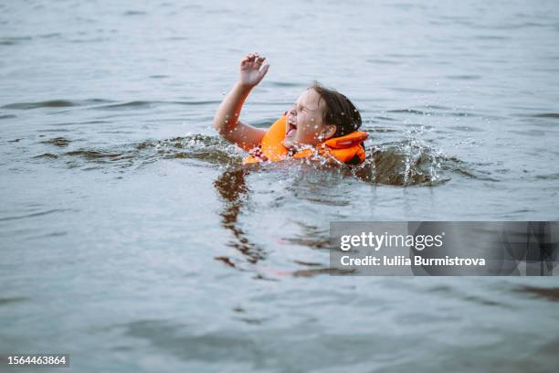 unattended child in life jacket screaming in panic struggling to stay on water surface. - life jacket stock pictures, royalty-free photos & images