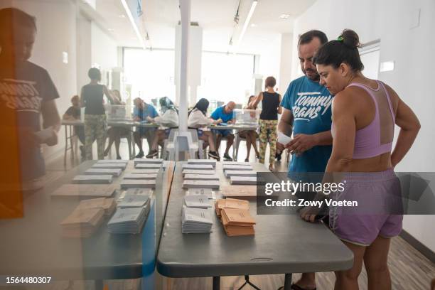 Couple about to go to the beach choose which political party to vote for on July 23, 2023 in Benidorm, Spain. Voters in Spain head to the polls on...