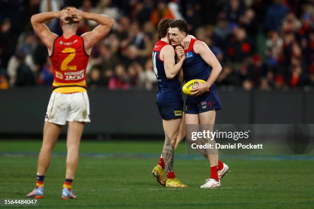 Ben Keays of the Crows looks dejected after whilst Jake Lever of the Demons and Trent Rivers of the Demons celebrate after winning the round 19 AFL...