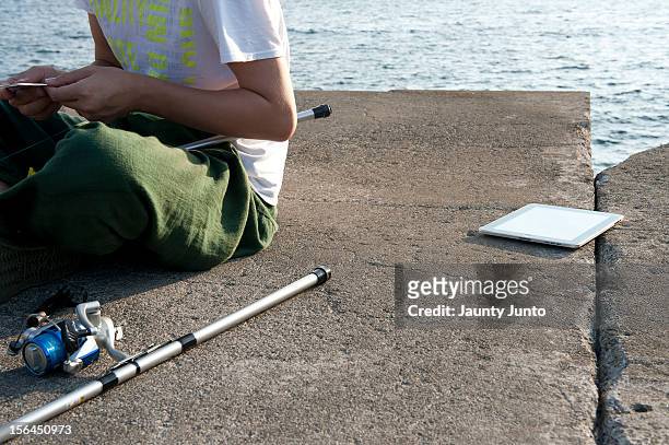 fishing with tablet computer - embankment stock pictures, royalty-free photos & images