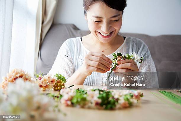 a woman making artificial flowers into corolla - flower arrangement stock pictures, royalty-free photos & images