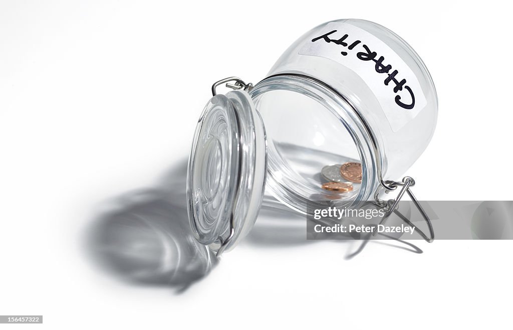 Nearly empty 'charity' jar on white background