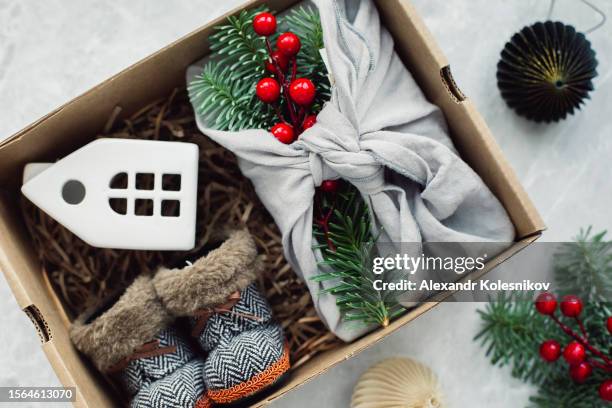 christmas furoshiki gift, white caramic house and cute small boots. zero waste christmas concept. flat lay - white house christmas stock pictures, royalty-free photos & images