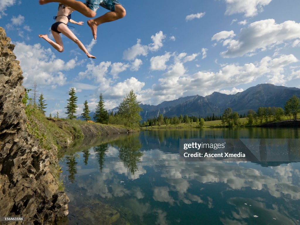 Legs of couple plunging towards a mountain lake