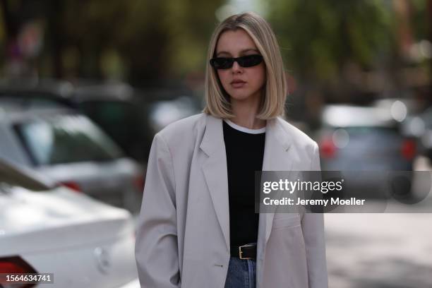 Isabelle Hartmann is seen wearing black narrow sunglasses from Saint Laurent, an oversize beige blazer from The Frankie Shop, underneath a black top...
