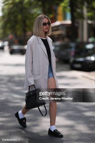 Isabelle Hartmann is seen wearing black narrow sunglasses from Saint Laurent, an oversize beige blazer from The Frankie Shop, underneath a black top...