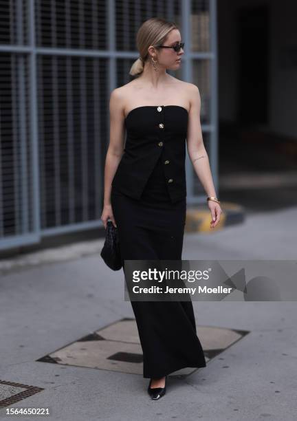 Isabelle Hartmann is seen wearing black narrow sunglasses from Saint Laurent, long golden ergs from Chanel, a sleeveless black top with golden...