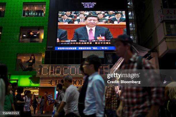 Pedestrians pass by a monitor showing a news broadcast of Xi Jinping, general secretary of the Communist Party of China, outside a store in the...