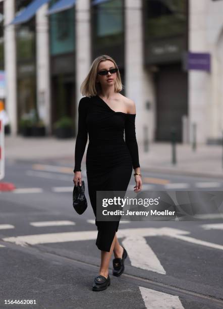 Isabelle Hartmann is seen wearing golden earrings from Yves Saint Laurent, black narrow sunglasses from Saint Laurent, a black one shoulder...