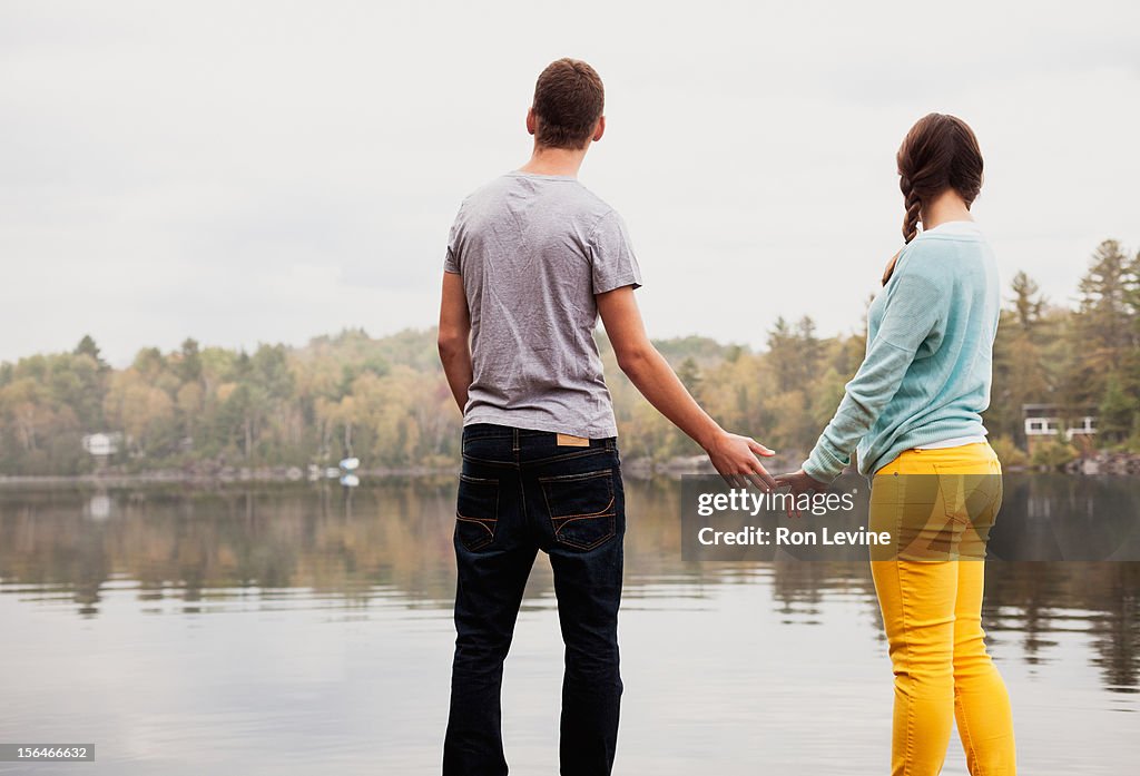 Teen couple holding hands by a lake