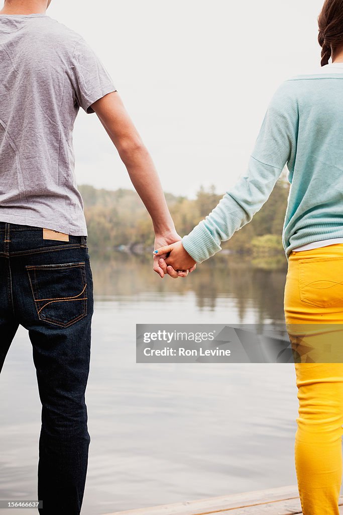 Teen couple holding hands by a lake