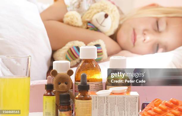 young girl poorly in bed with medication on table - antibiotikum stock-fotos und bilder