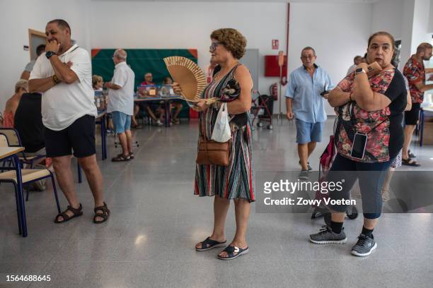 Aurora Gálvez, holds a hand fan, as she queues up with her dog to vote in the general elections at Leonor Canalejas public school on July 23, 2023 in...