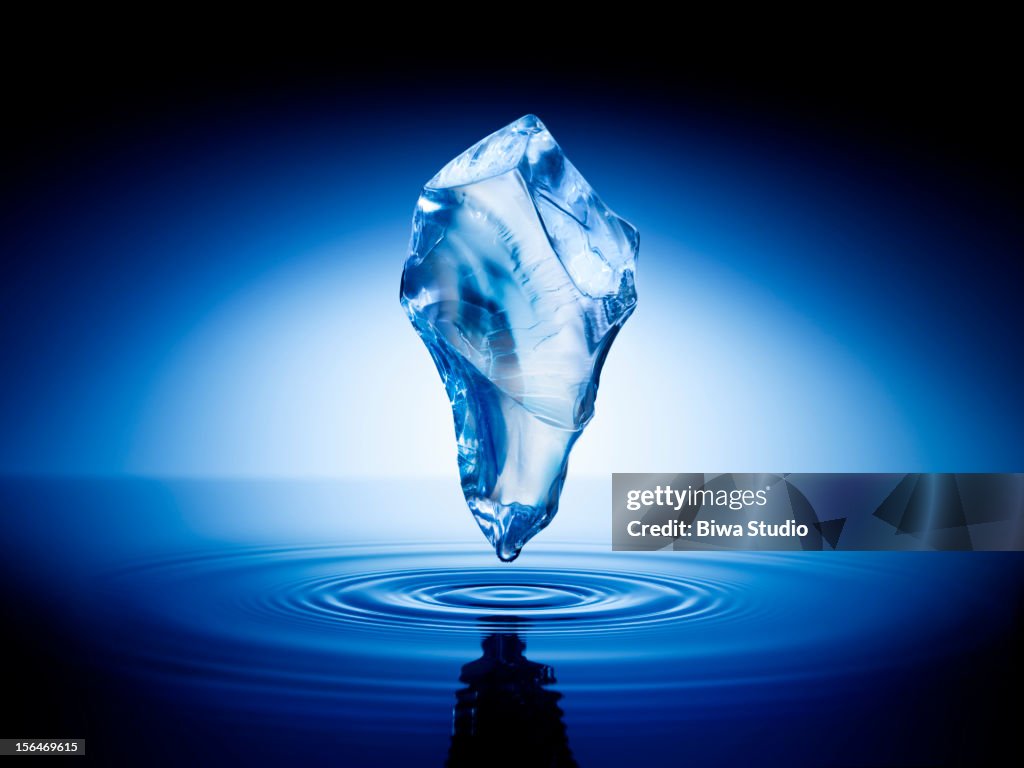 Ice cube floating in the air over water surface