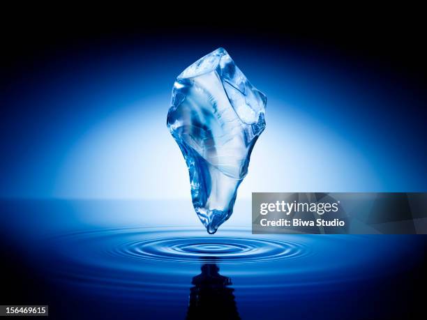 ice cube floating in the air over water surface - ice stock pictures, royalty-free photos & images