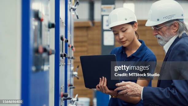 los ingenieros industriales profesionales hablan con el trabajador de la fábrica mientras usan una computadora portátil en la fábrica de fabricación. trabajando en planta de fabricación o planta de producción. - operational technology fotografías e imágenes de stock