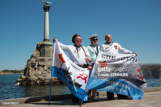 Woman poses for pictures with two veteran sailors in front of the Sunken Ships Monument in Sevastopol, Crimea, during Russia's Navy Day celebrations...