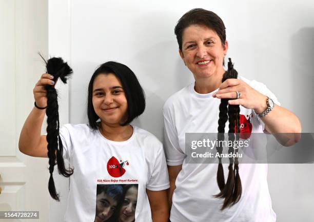 Year-old Seher Karakus and 61-year-old Sadiye Kilic pose for a photo holding their braided hair after getting them cut at a hairdresser's in Ankara,...