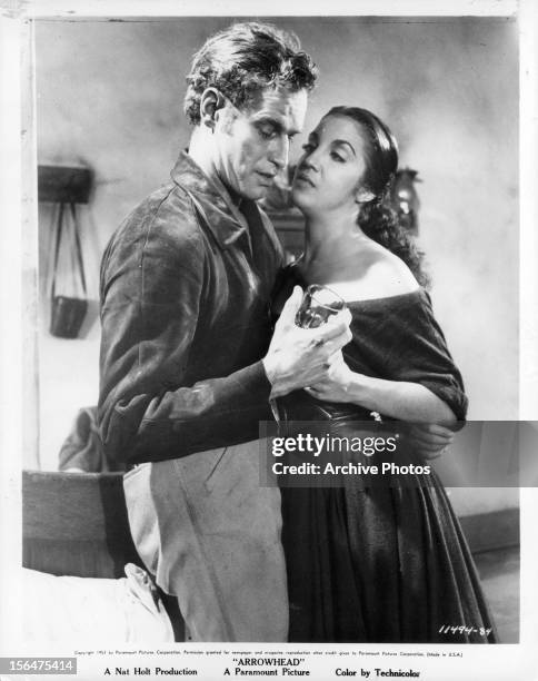 Charlton Heston pulling Katy Jurado close to him in a scene from the film 'Arrowhead', 1953.