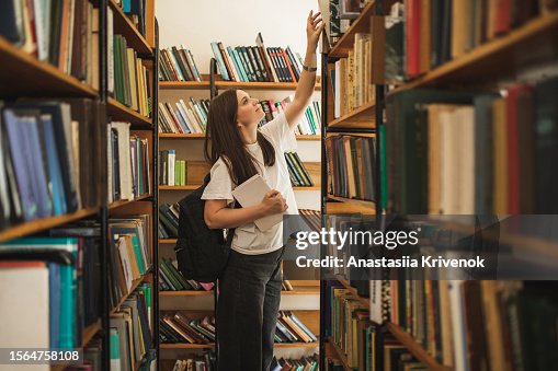 Portrait of female student looking for special book in library. Portrait of female student looking for special book in library.