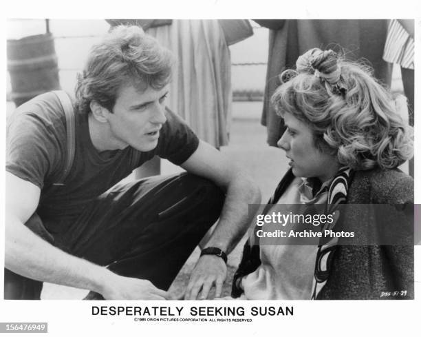 Aidan Quinn kneels beside Rosanna Arquette in a scene from the film 'Desperately Seeking Susan', 1985.