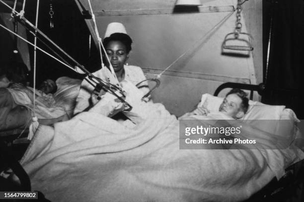 American military nurse Lieutenant Florie E Grant, of the Army Nurse Corps, tends to a German prisoner of war who had undergone orthopaedic surgery...
