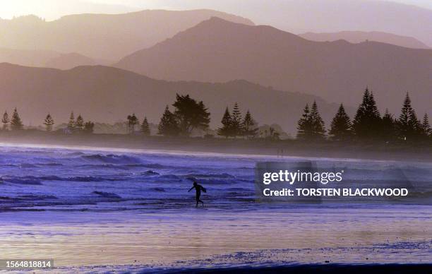 Lone surfer braves the icy waters of Poverty Bay at Gisborne's Waikanae Beach, 30 November 1999, where local girl and soprano diva Dame Kiri Te...