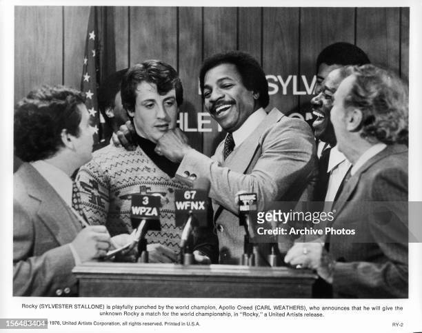 Sylvester Stallone takes a hit from Carl Weathers at a press conference in a scene from the film 'Rocky', 1976.