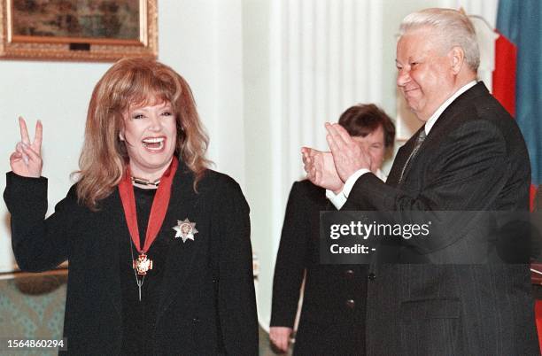 Russian President Boris Yeltsin applauds as famous Russian pop star Alla Pugacheva gives a V-sign after receiving the Merit for Fatherland order in...
