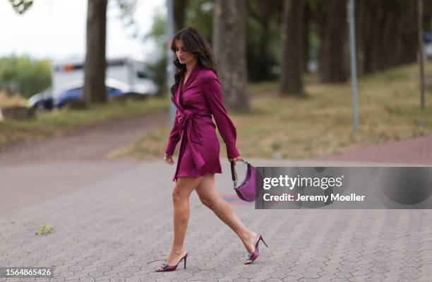 Merna Hermez is seen wearing a complete Riani outfit, consisting of a long-sleeved wrapped mini dress in purple, a purple/glitter bag and pumps...