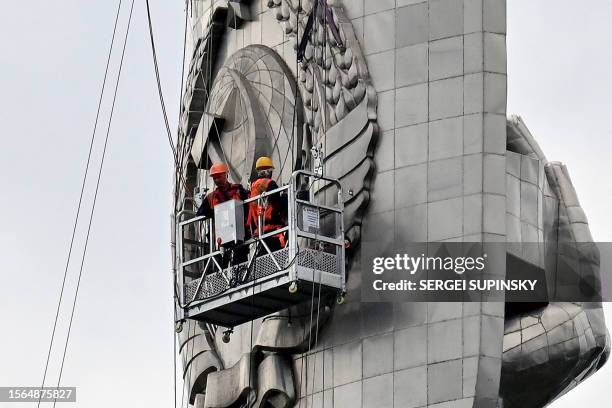 Steeplejacks dismantle the coat of arms of the former Soviet Union from the shield of a 62-meter Motherland Monument in Kyiv on July 30, 2023. The...