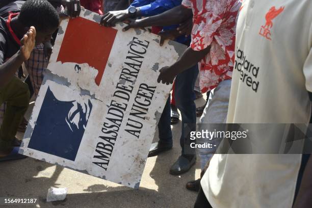 Protesters hold a sign taken from the French Embassy in Niamey during a demonstration that followed a rally in support of Niger's junta in Niamey on...