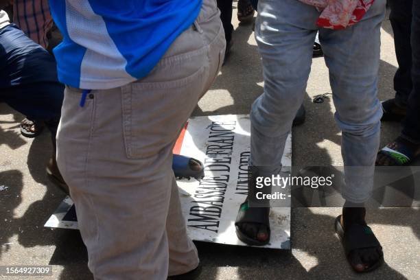 Protesters stomp over a sign taken from the French Embassy in Niamey during a demonstration that followed a rally in support of Niger's junta in...