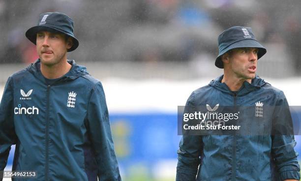 England players Stuart Broad and James Anderson look on as they leave the field after a game of head tennis in the rain as the start of play is...