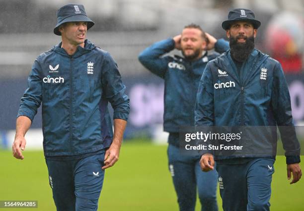 England players James Anderson Ben Duckett and Moeen Ali look on as they leave the field after a game of head tennis in the rain as the start of play...