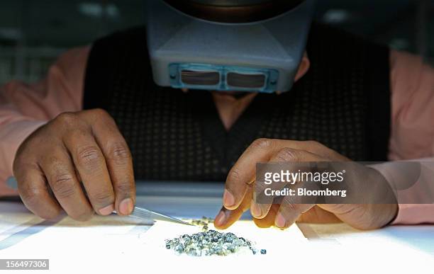 An employee sorts through a pile of uncut diamonds during the grading process in the sorting room at DTC Botswana, a unit of De Beers, in Gaborone,...
