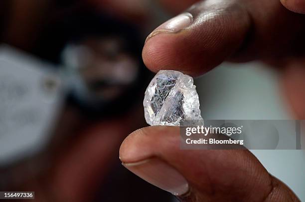 An employee looks at an uncut diamond through a magnifying glass at DTC Botswana, a unit of De Beers, in Gaborone, Botswana, on Thursday, Oct. 25,...