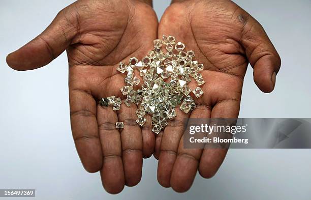 An employee displays a handful of uncut diamonds in this arranged photograph at DTC Botswana, a unit of De Beers, in Gaborone, Botswana, on Thursday,...