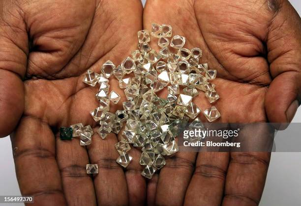 An employee displays a handful of uncut diamonds in this arranged photograph at DTC Botswana, a unit of De Beers, in Gaborone, Botswana, on Thursday,...