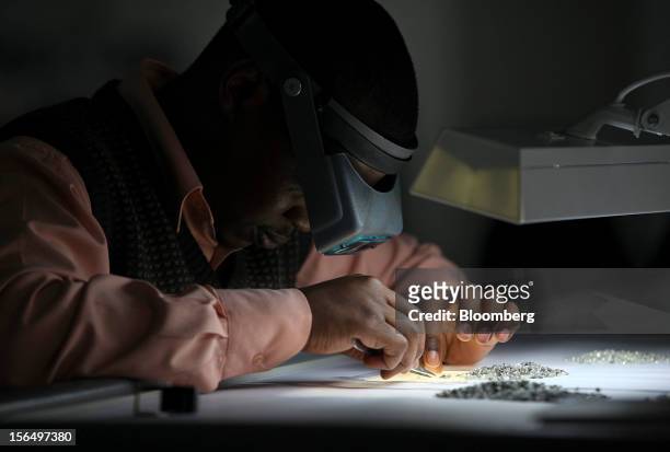 An employee uses an angled light and a magnifier to sort uncut diamonds at a sorting table in DTC Botswana, a unit of De Beers, in Gaborone,...
