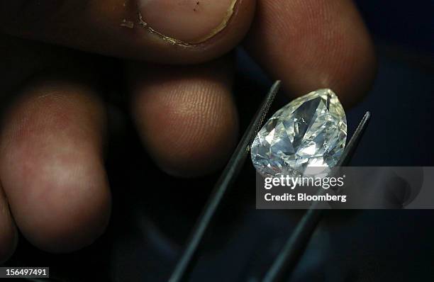 Finished pear-shaped diamond is displayed by an employee using tweezers in this arranged photograph at the Shrenuj Botswana Ltd. Sightholder office...