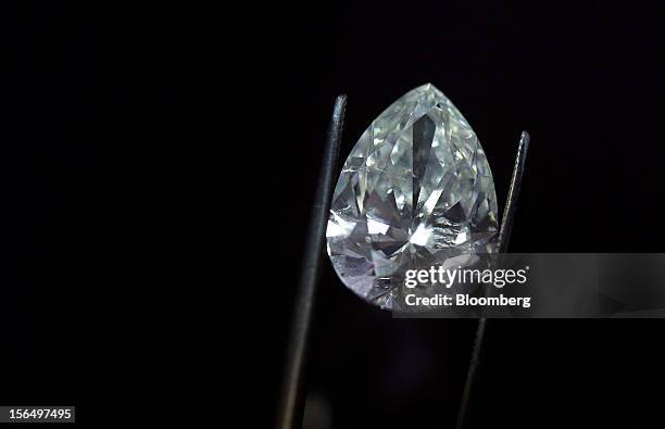 Finished pear-shaped diamond is displayed by an employee using tweezers in this arranged photograph at the Shrenuj Botswana Ltd. Sightholder office...