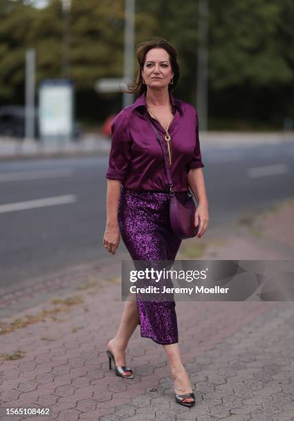 Natalia Wörner is seen wearing a complete Riani outfit, consisting of a purple shirt, a purple midi skirt with sequins, a purple bag and shiny silver...