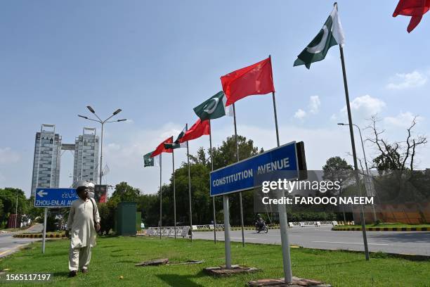 Man walks past China's and Pakistani national flags installed on the constitution avenue ahead of the visit of Chinese Vice Premier He Lifeng, in...