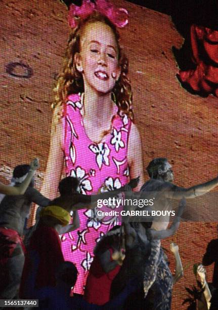 Young performer Nikki Webster appears on a giant screen as Aboriginal dancers perform on the grounds of the Olympic Stadium 15 September, 2000 during...