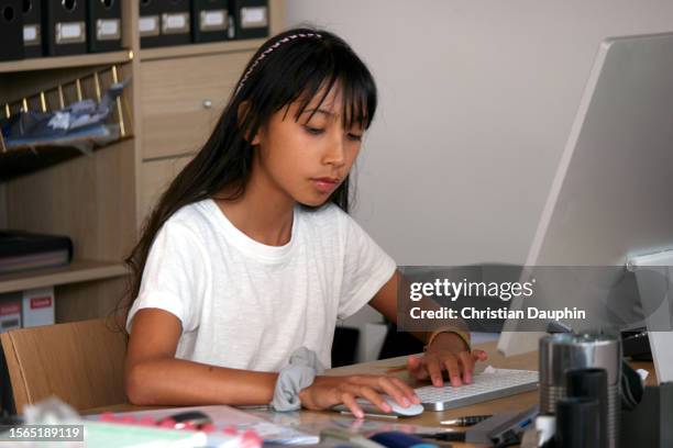 a mixed-race teenager works on school work on her computer - niveau d'éducation stock pictures, royalty-free photos & images