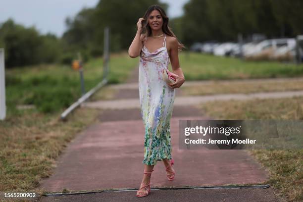 Bruna Rodrigues is seen wearing a pastel coloured midi dress with watercolour print from Riani, a pink bag and pink strap sandals outside during the...